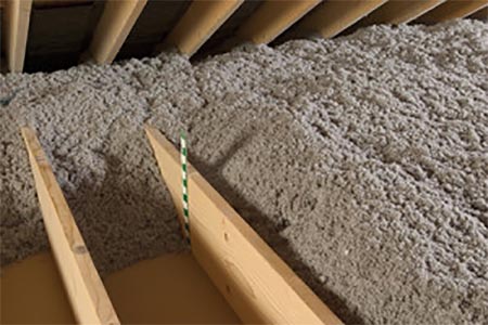 Loose-fill cellulose attic insulation between wooden joists