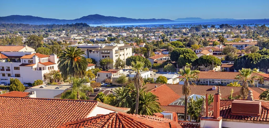 Aerial view of Santa Barbara homes with red tile roofs and ocean in the background.