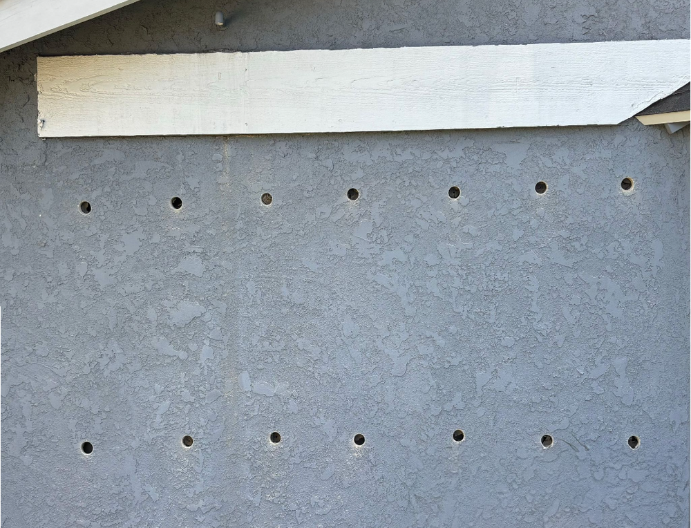 Exterior wall with holes for insulation installation.