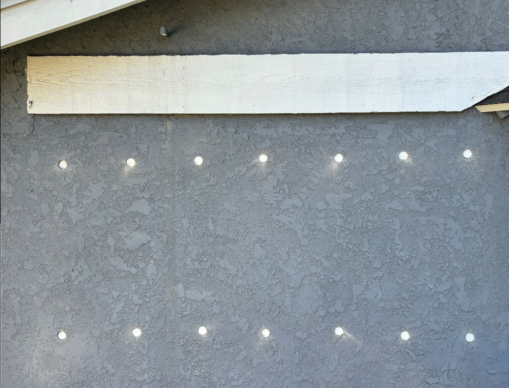 Exterior wall with stucco finish and embedded lights, possibly showing insulation.