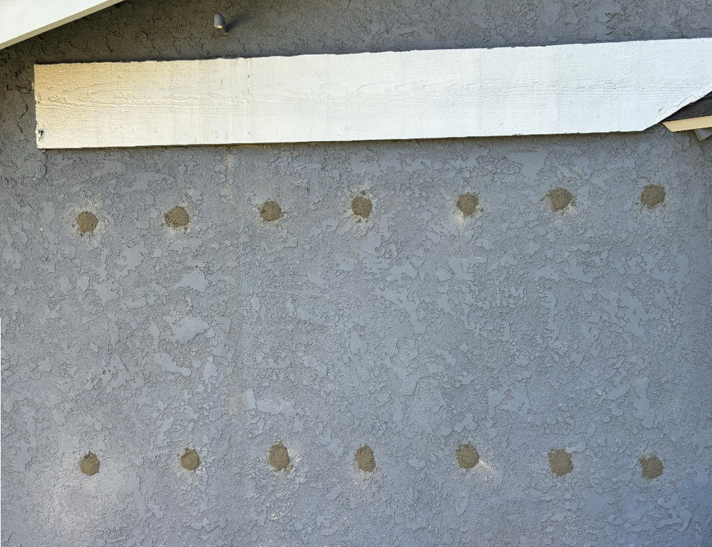 Exterior wall with small, circular patches of exposed insulation