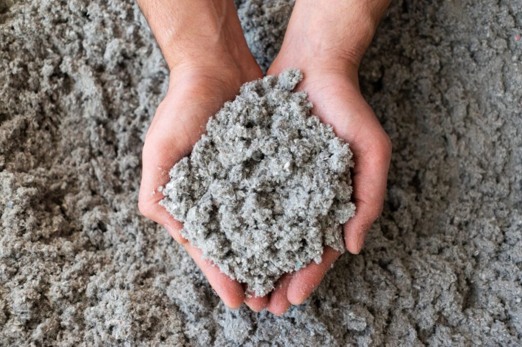 Hands holding cellulose insulation, a common eco-friendly building material.