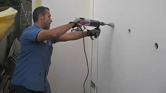 Man drilling holes in wall for insulation installation
