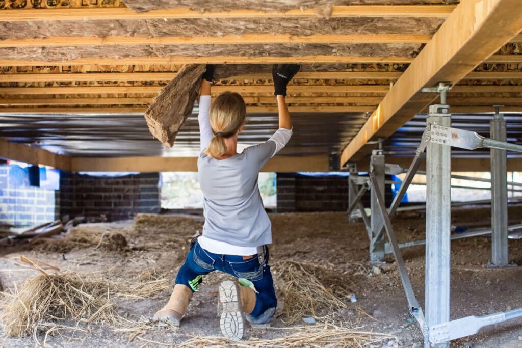 Woman installing attic insulation between ceiling joists